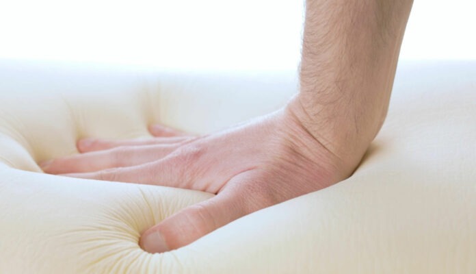 Hand pressing into a memory foam mattress.